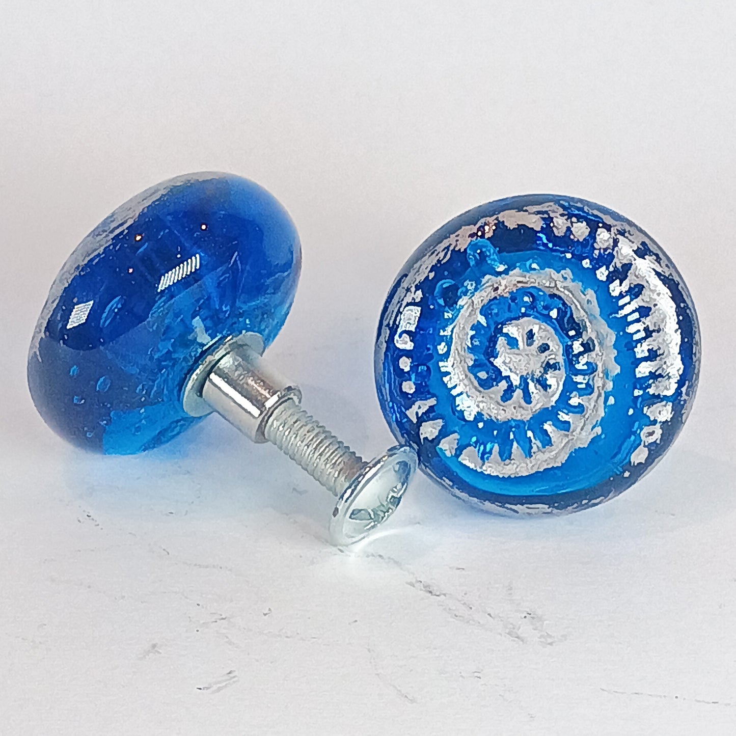Two blue glass knobs with intricate designs 
