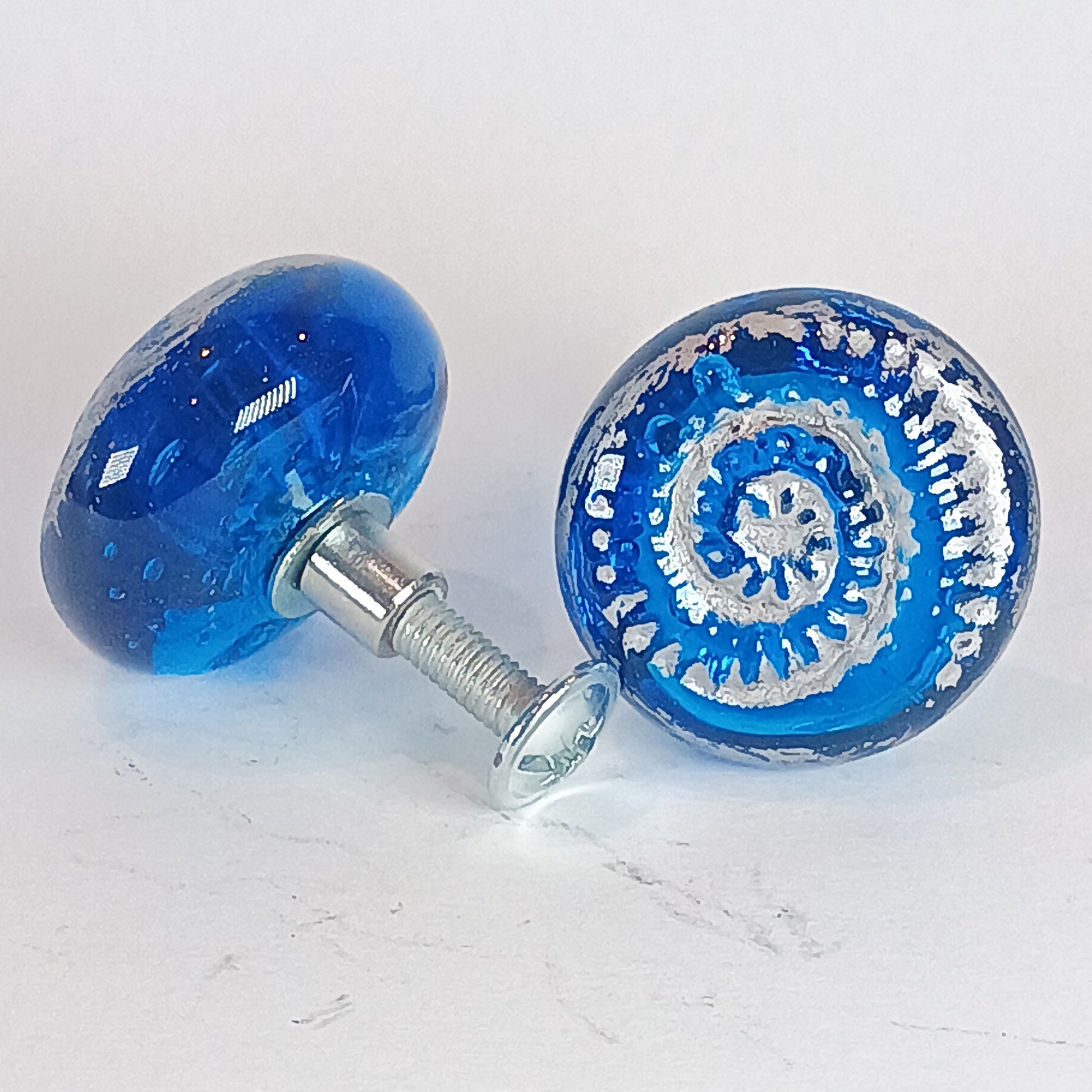 Two blue glass knobs with intricate designs 