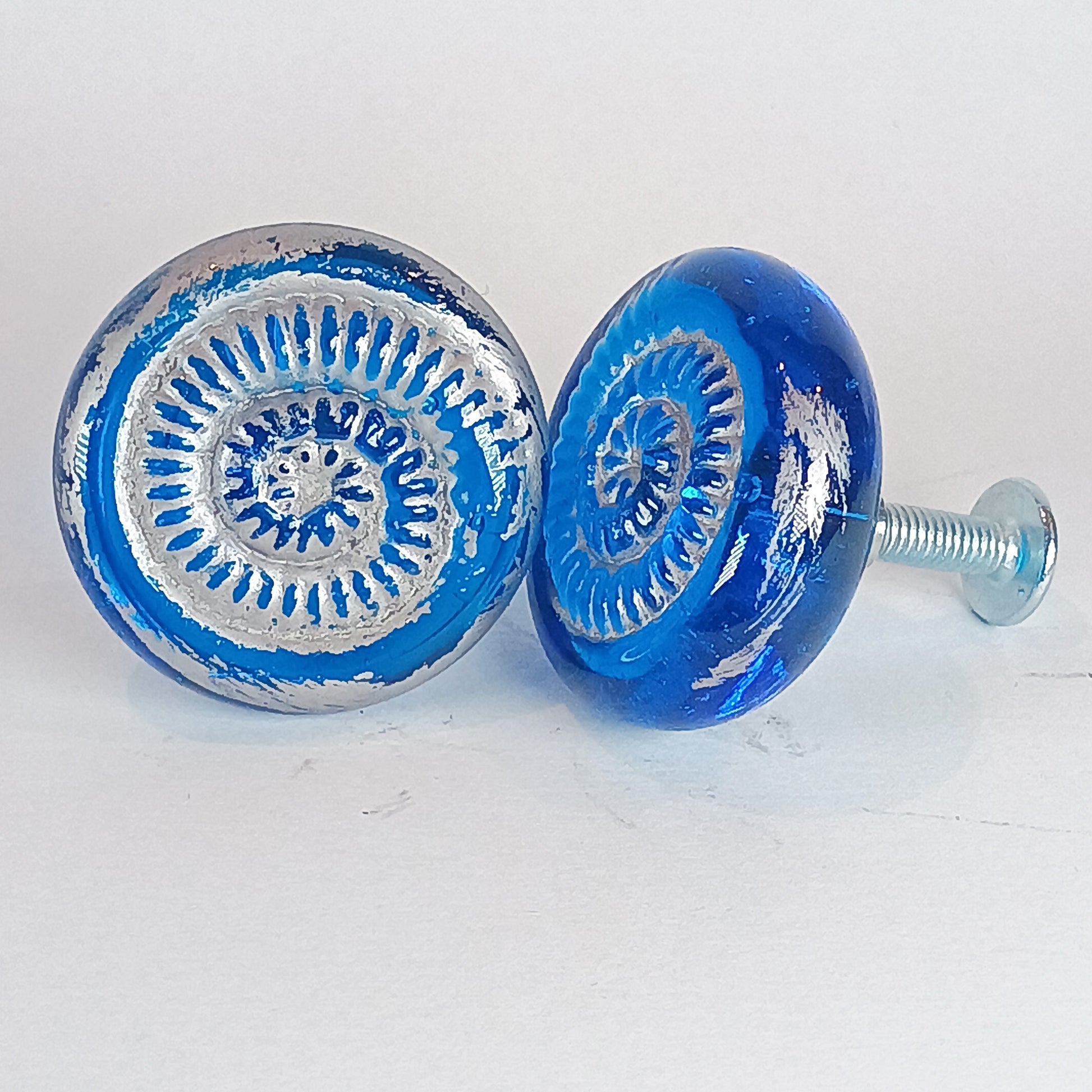 Two blue glass cabinet knobs with silver patterns 