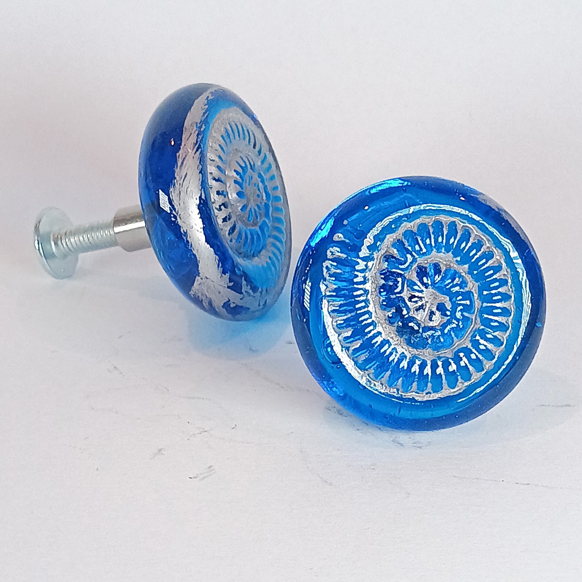 Two blue glass knobs with decorative  sliver ammonite texture