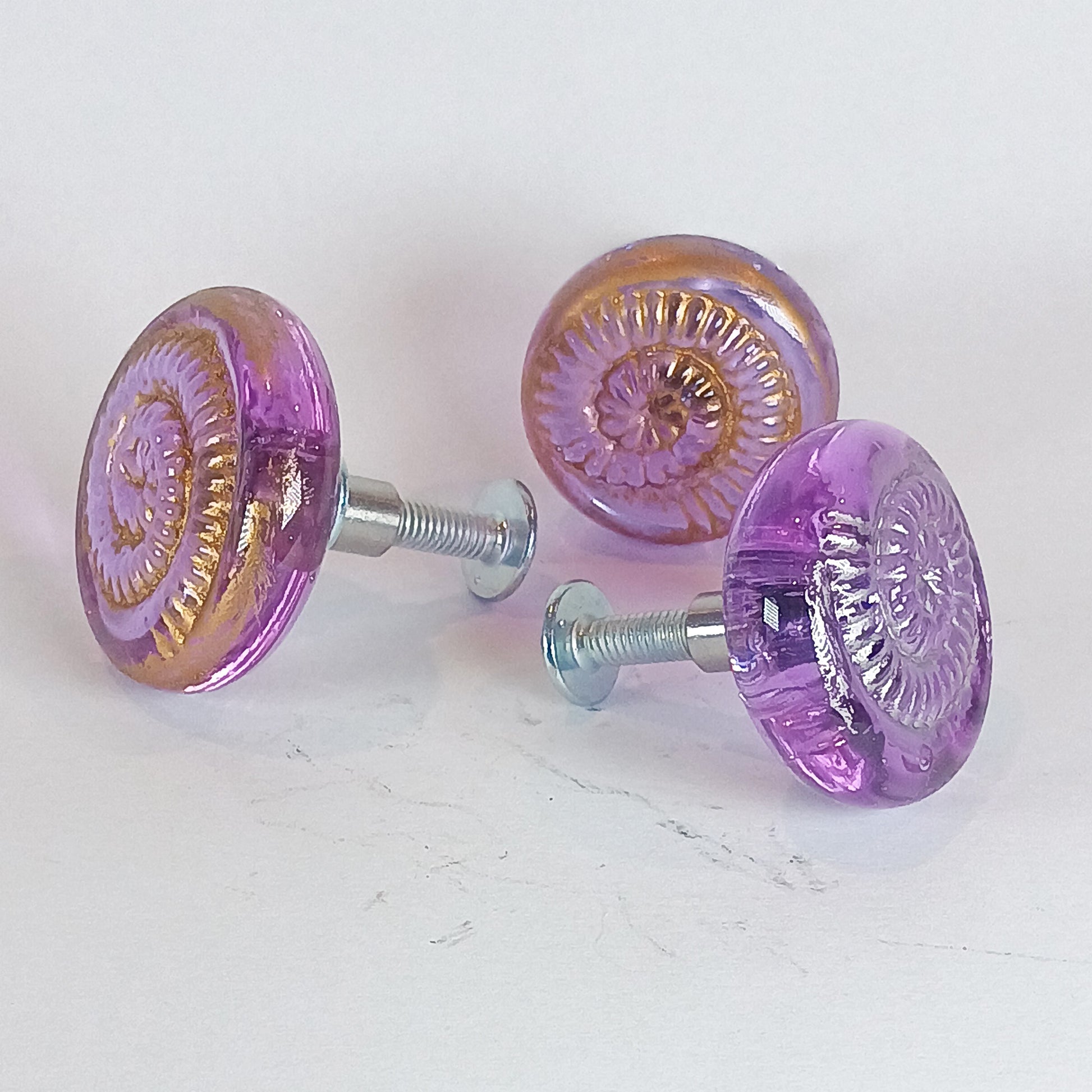 Purple glass cabinet and drawer knobs with ammonite texture and gold or silver detail